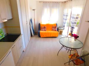 sala de estar con silla naranja y mesa de cristal en GMID IMMO Apartment Castell Joncar, en Roses