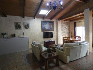 a living room with couches and a television and a table at Alojamientos Monteverde in Oj&eacute;n