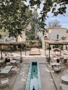une cour avec des tables, des chaises et une fontaine dans l'établissement Hôtel Le Saint Remy & Spa, à Saint-Rémy-de-Provence