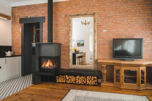 a brick fireplace with a television and a mirror at Berchy Apartment 3 in Liepāja