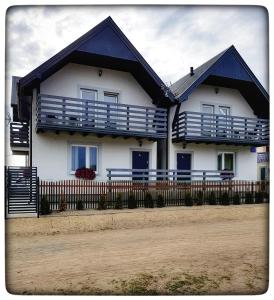 une maison blanche avec des balcons bleus et une clôture dans l'établissement Siodemkacamp Karwia, à Karwia