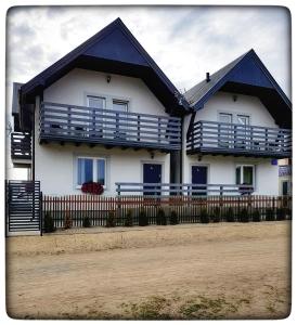 a white house with blue balconies and a fence at Siodemkacamp Karwia in Karwia