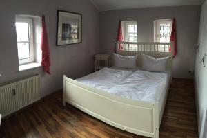 施特拉尔松德Altes Zollhaus Stralsund的带2扇窗户的客房内的一张白色床