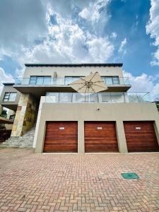 a house with two garage doors and an umbrella at RNB Guesthouse in Roodepoort