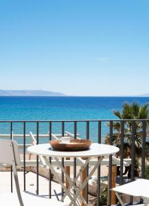 einen Tisch und Stühle auf einem Balkon mit Meerblick in der Unterkunft Magoo Suites in Logaras
