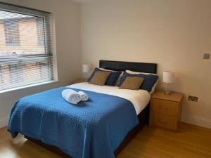 a bedroom with a large bed with a blue blanket at 2 bed 2 baths in a central location ☆☆☆☆☆ in Basingstoke