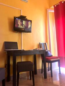 Un escritorio con una computadora portátil y un televisor en una pared. en Templar Secrets House Beach, en Nazaré