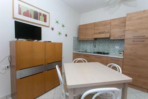 eine Küche mit Holzschränken und einem Tisch mit Stühlen in der Unterkunft RS321 - Marcelli, trilocale fronte mare con spiaggia inclusa in Marcelli