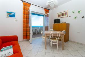 ein Wohnzimmer mit einem roten Sofa und einem Tisch mit Stühlen in der Unterkunft RS321 - Marcelli, trilocale fronte mare con spiaggia inclusa in Marcelli