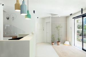 a white kitchen with potted plants and pendant lights at Domìa Boutique Hotel e Cucina in Mondello