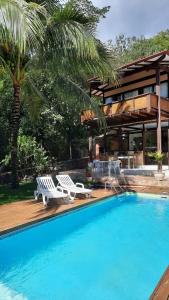 a swimming pool with two lounge chairs and a house at Moana Ilhabela in Ilhabela