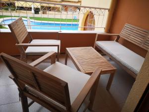 2 Stühle und eine Bank auf einem Balkon mit Pool in der Unterkunft Retiro de Levante in Santa Pola
