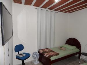 a room with a bed and a tv and a chair at Hospedagem Progresso in Juiz de Fora