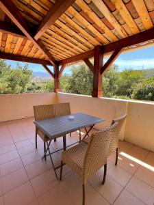 a table and chairs on a porch with a wooden roof at Hôtel L'Escale Coté Port in LʼÎle-Rousse
