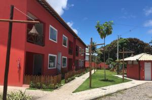 een rood gebouw met een hek naast een straat bij Ecoville das Mangueiras - Condomínio em Monte Gordo - Região de Guarajuba in Camassari