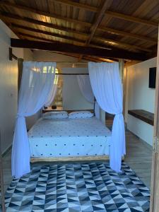 - une chambre avec un lit avec des rideaux et un sol en damier dans l'établissement Chales em Salesopolis - Recanto da Barra, à Salesópolis