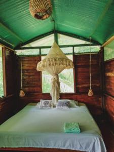 Cama en habitación con techo verde en K'erenda Homet Reserva Natural en Puerto Maldonado