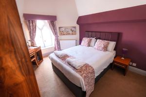 a bedroom with a large bed with purple walls at The Lemon Tree in Wrexham +20 photos