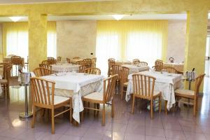 um restaurante com mesas e cadeiras com toalhas de mesa brancas em Hotel Parthenius em Cirella
