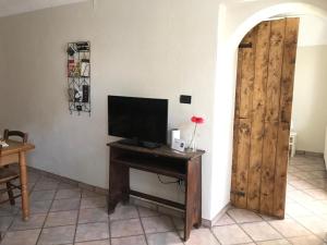 a room with a television and a wooden door at Appartamento i Tulusan a due passi dalle Langhe in Narzole