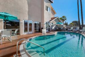 a swimming pool with chairs and umbrellas next to a building at Comfort Inn San Diego Miramar in Miramar