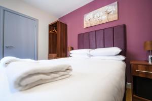 a bedroom with a large white bed with purple walls at The Lemon Tree in Wrexham