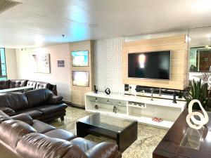 uma sala de estar com um sofá e uma televisão de ecrã plano em LOFT LUXO VISTA MAR PRAINHA até 5 PESSOAS em Arraial do Cabo