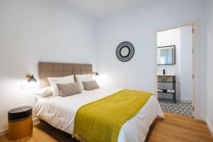 1 dormitorio blanco con 1 cama grande con manta amarilla en Magno Apartments Alameda 1851 - Shared jacuzzi en Sevilla