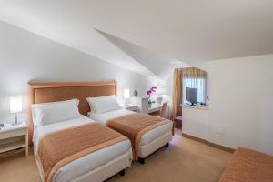 a hotel room with two beds and a television at Park Hotel Olimpia in Brallo di Pregola