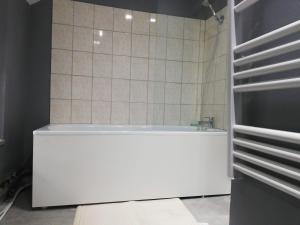 ein Badezimmer mit einer weißen Badewanne und einer gefliesten Wand in der Unterkunft Duplex Savane, Lille in Lille