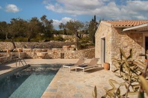 a pool with two chairs next to a stone wall at Villa Sirina in Magaziá
