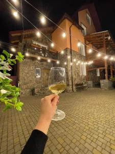 Eine Person, die ein Glas Wein hochhält in der Unterkunft Садиба Рокса з басейном in Slawske