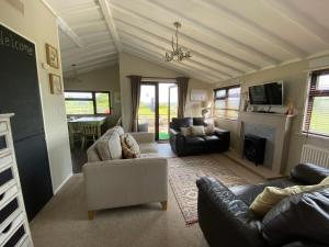 a living room with two couches and a fireplace at Rew Farm Country & Equestrian Accommodation - Sunrise Lodge in Melksham