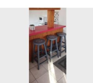 a kitchen with a red counter and bar stools at Hippo Farm Apartment in Gobabis