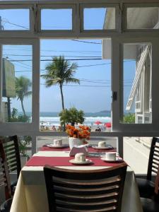 uma mesa com vista para a praia através de uma janela em Costa Maris Beach Hotel Frente Mar no Guarujá