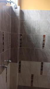 a bathroom with a shower with brown tile at Hostería La Chorrera in Quito