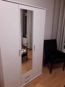 un armario blanco con espejo y silla en Ferienwohnung Chemnitz - Kaßberg en Chemnitz