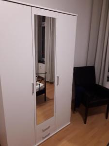 a white cabinet with a mirror and a chair at Ferienwohnung Chemnitz - Kaßberg in Chemnitz