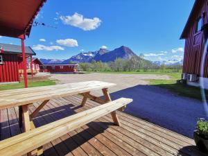 a wooden bench on a deck with mountains in the background at Reipå Camping in Reipå
