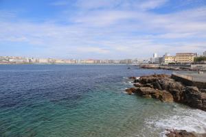 ein großer Wasserkörper mit einer Stadt im Hintergrund in der Unterkunft Apartamento Orzán playa in A Coruña