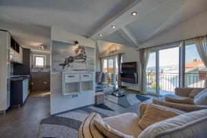 a living room with a couch and a kitchen with windows at Porto View Three-Bedroom Duplex in Tivat