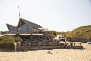 a building on a beach with people on the sand at Spacious villa near a lake in Bredene