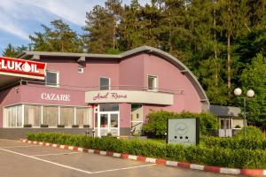 a pink building with a carpark in front of it at Hotel Amel Rooms in Mediaş