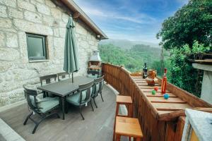eine Terrasse mit Tisch und Stühlen und einem Sonnenschirm in der Unterkunft Lamegos GuestHouse - Gerês in Terras de Bouro