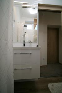 - une cuisine blanche avec un évier et un miroir dans l'établissement Otium Wellness Apartmanház, à Balatonakarattya