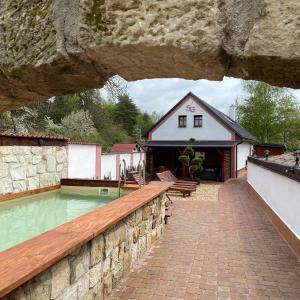 a house with a swimming pool and a stone wall at SG chalupa ŠTIKOV - Podkrkonoší - s celoročním privátním wellness in Nová Paka