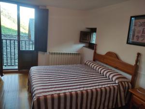 1 dormitorio con 1 cama con manta a rayas en Centro Torla-Ordesa 5pax Apto Miguel en Torla