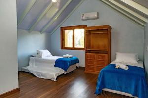 グラマドにあるLocar-in Gramado - Chácara Bela Vistaのベッド2台とドレッサーと窓のある寝室