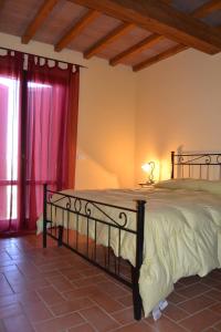 a bedroom with a large bed with red curtains at Agriturismo Beveraggio Appartamenti in Marina di Grosseto