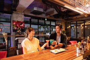 a man and a woman sitting at a bar at Hotel Cocktail Stay Naha in Naha